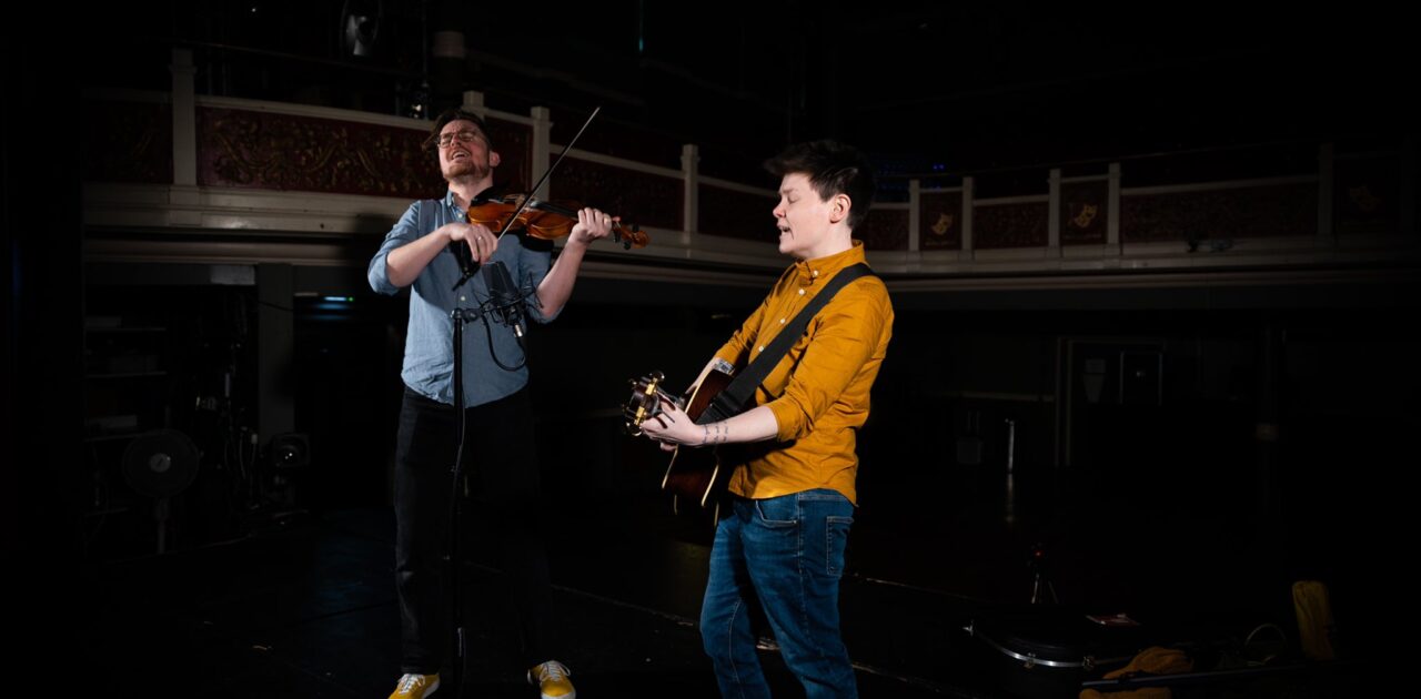 Leicester singer/songwriter Grace Petrie on stage mid-performance with violinist Ben Moss