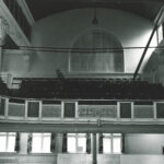 The Y Theatre before the bar was added, with windows at the back of the auditorium and the high chuch-like window. A blurry man (or ghost!) walks among the balcony seats.