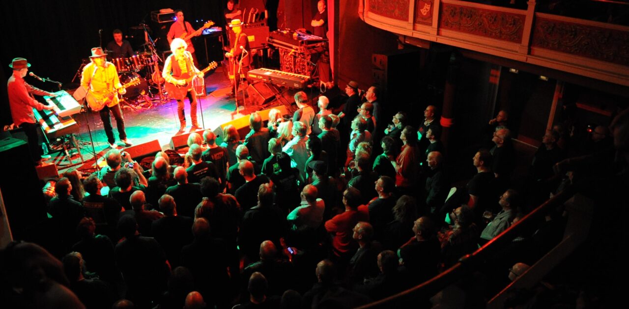 A photo taken from the balcony of a band on stage with a full standing audience